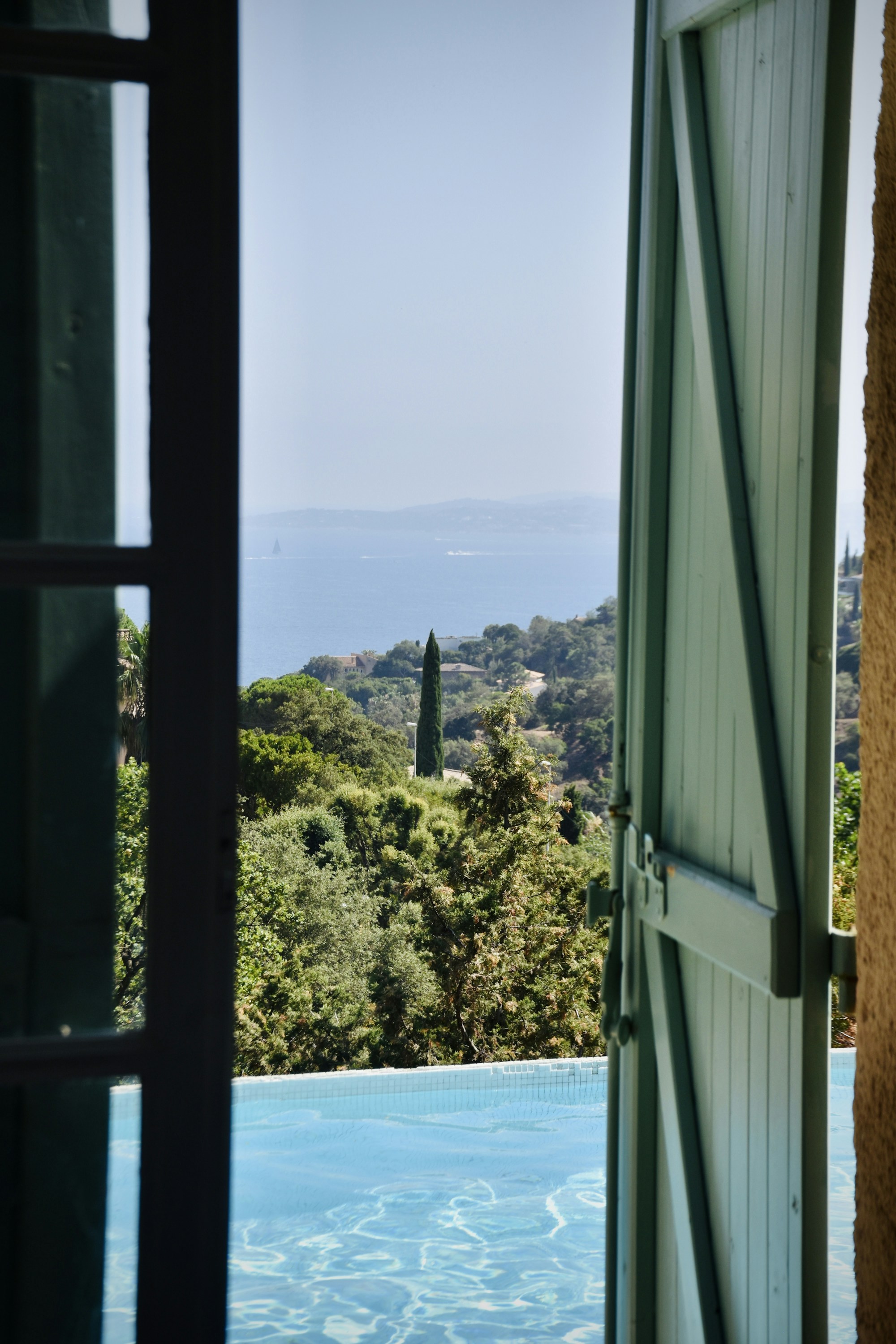 Vue depuis une villa : piscine à débordement, cyprès et mer turquoise (photo Arno Senoner, Unsplash)